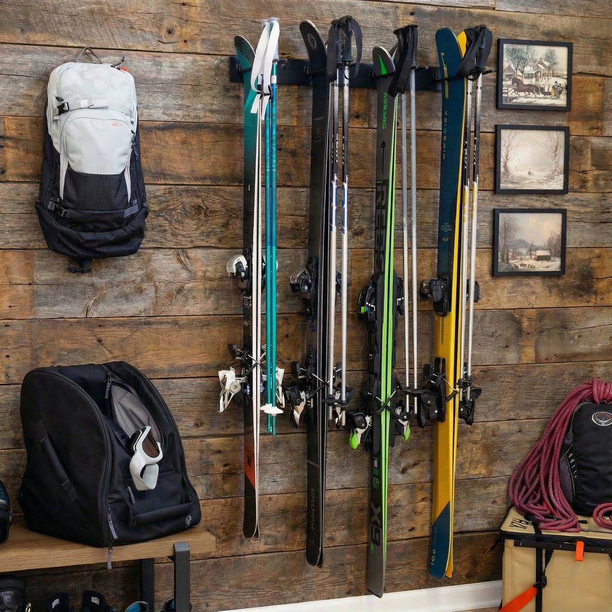 Skis stored on the Snowbasin rack on a wood plank wall beside boot bags
