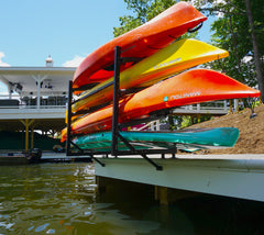 Four kayaks and a paddleboard stored on the Chesapeake rack at the edge of a dock