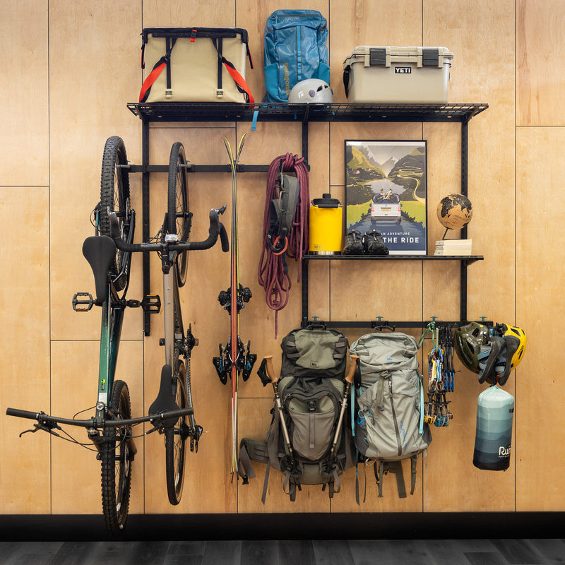 G-Adventure Pro wall system holding bikes, backpacks, a lantern and outdoor gear
