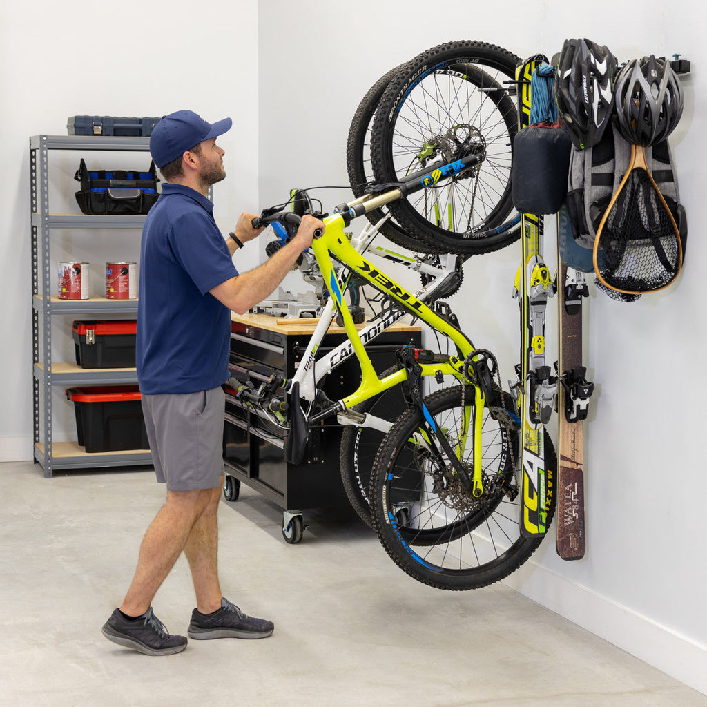 Man hanging a bike on the G-Adventure wall rack in a garage