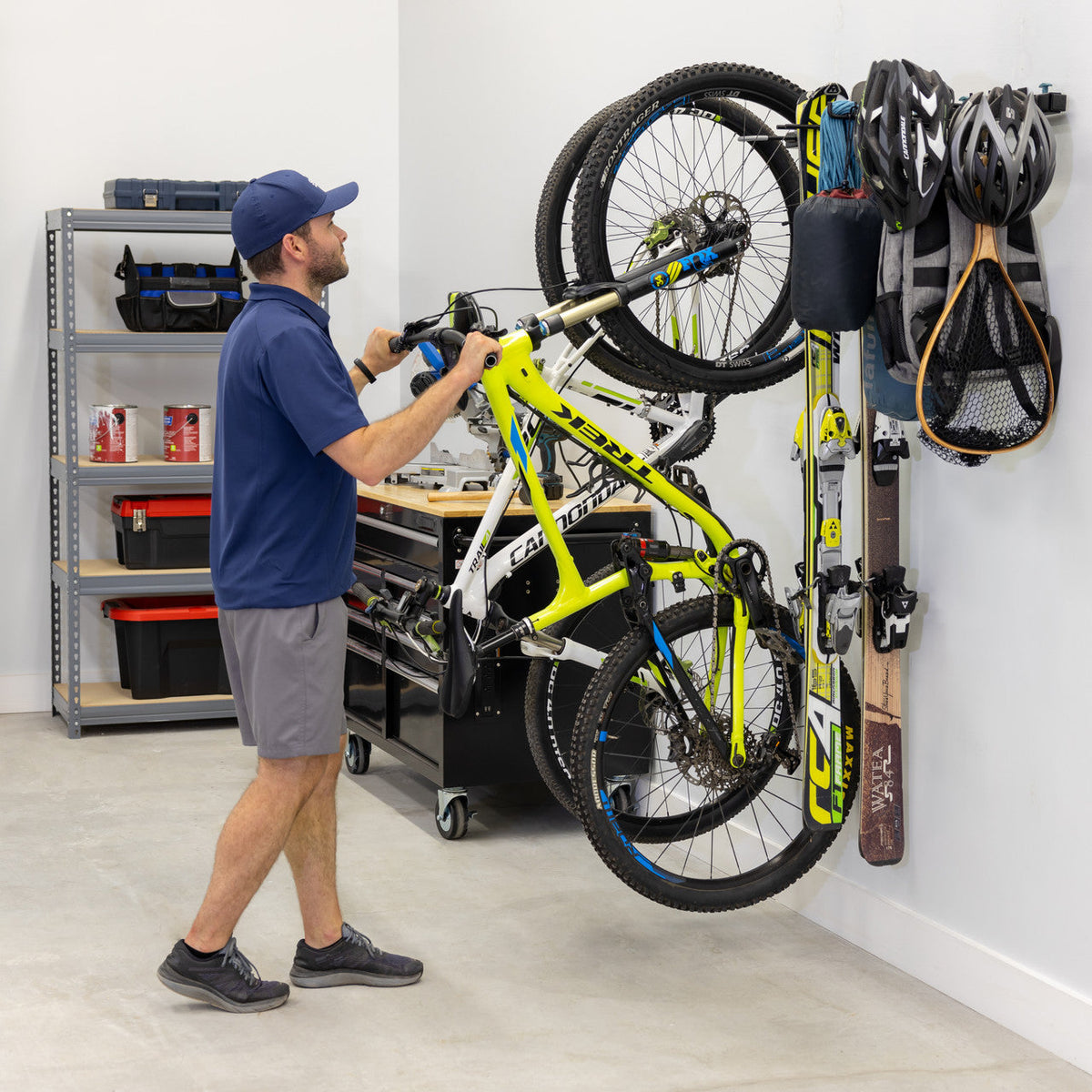 Man hanging a bike on the G-Adventure wall rack in a garage