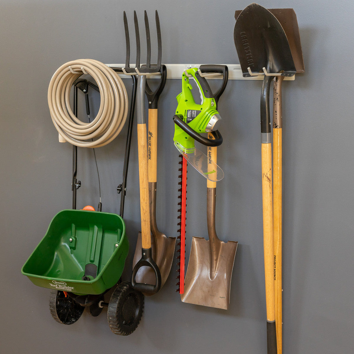 Gray tool organizer holding a hose, pitchfork, hedge trimmer, shovel and spreader