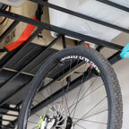Close-up of a bike wheel hanging from a ceiling shelf hook