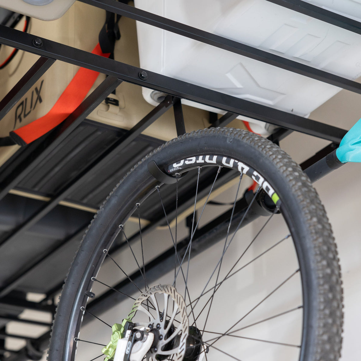Close-up of a bike wheel hanging from a ceiling shelf hook