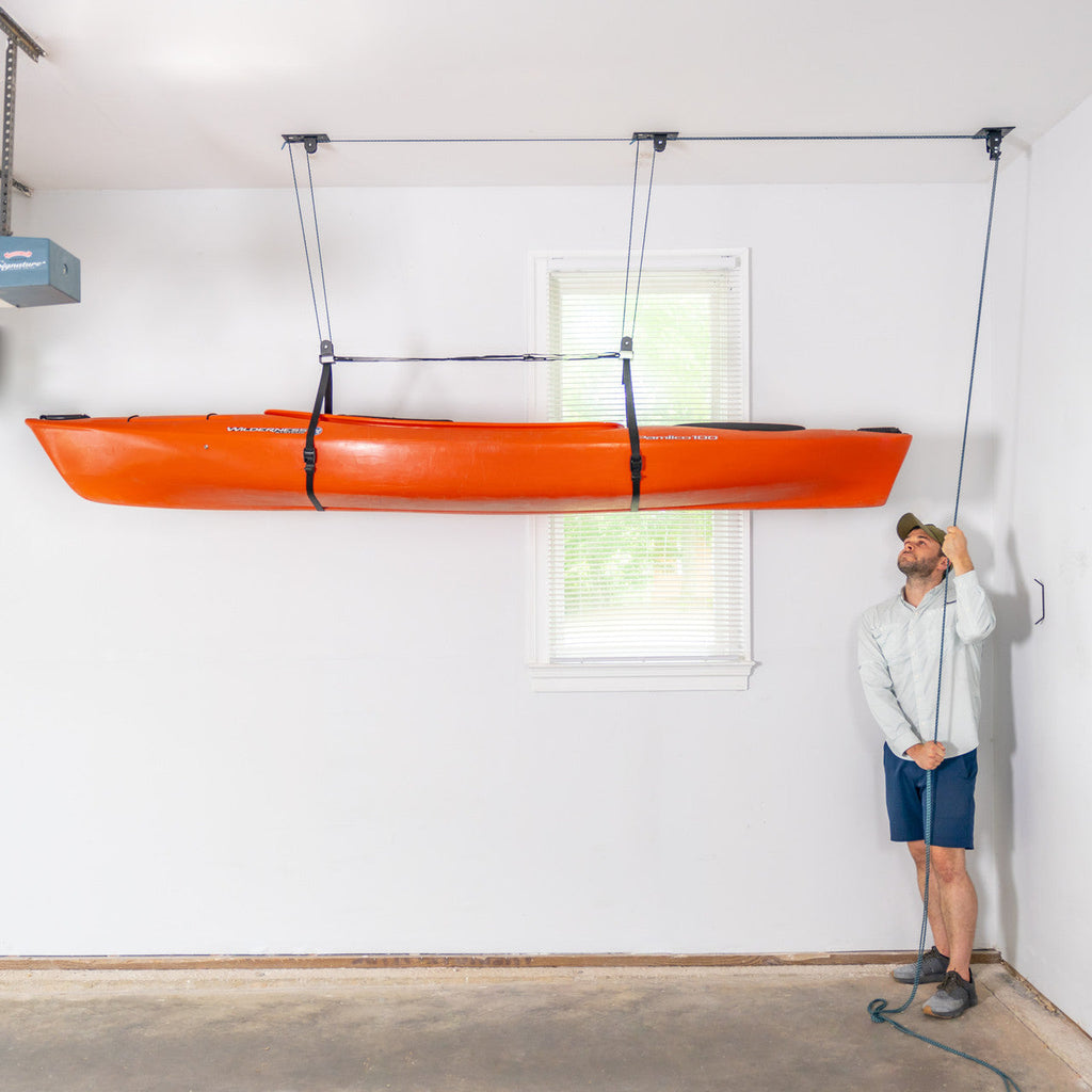 Man raising an orange kayak to the ceiling with the EasyLift hoist
