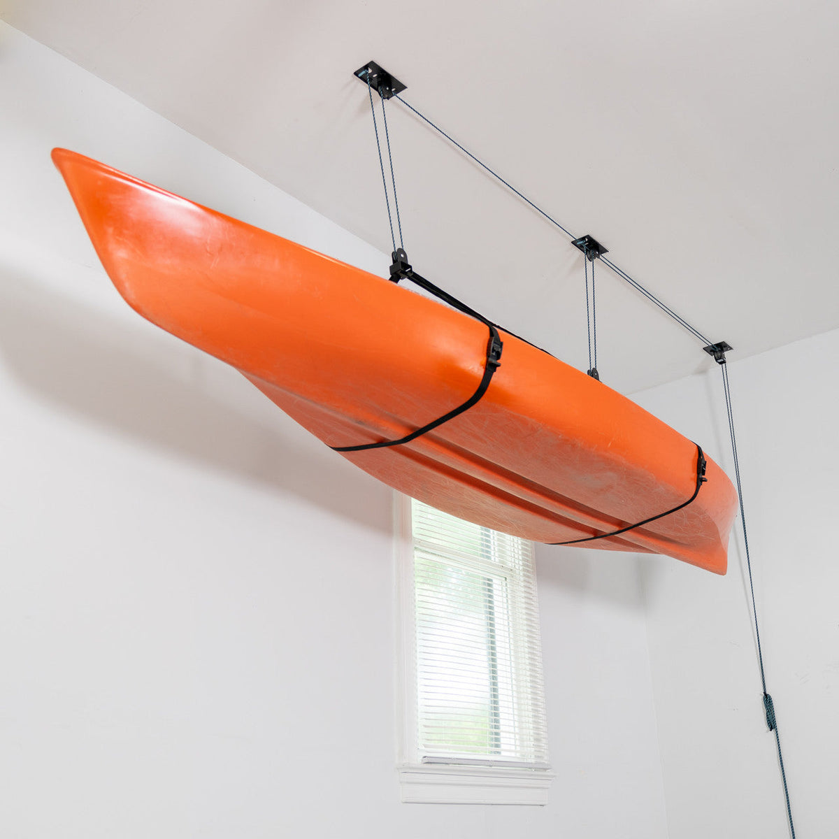 Orange kayak stored near the ceiling on the hoist