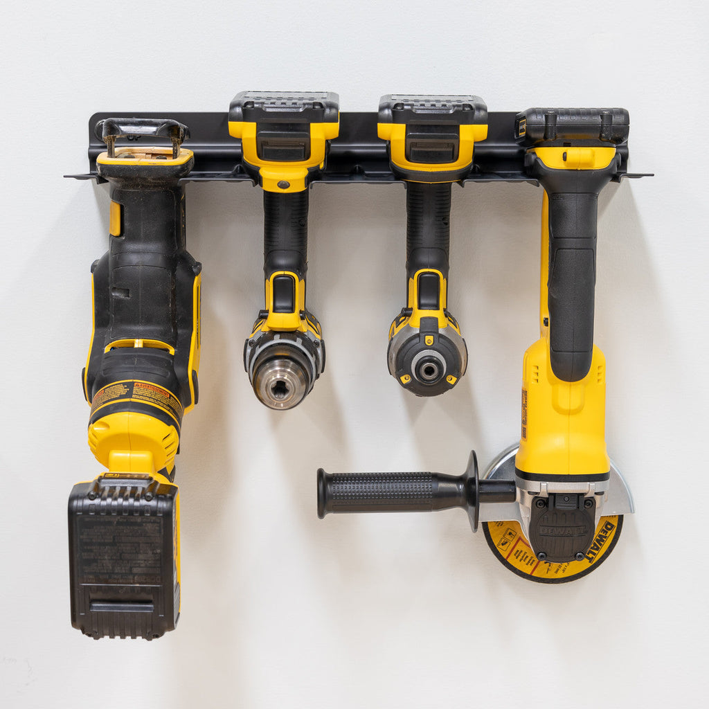 Cordless drills and an angle grinder hanging in the four-slot rack