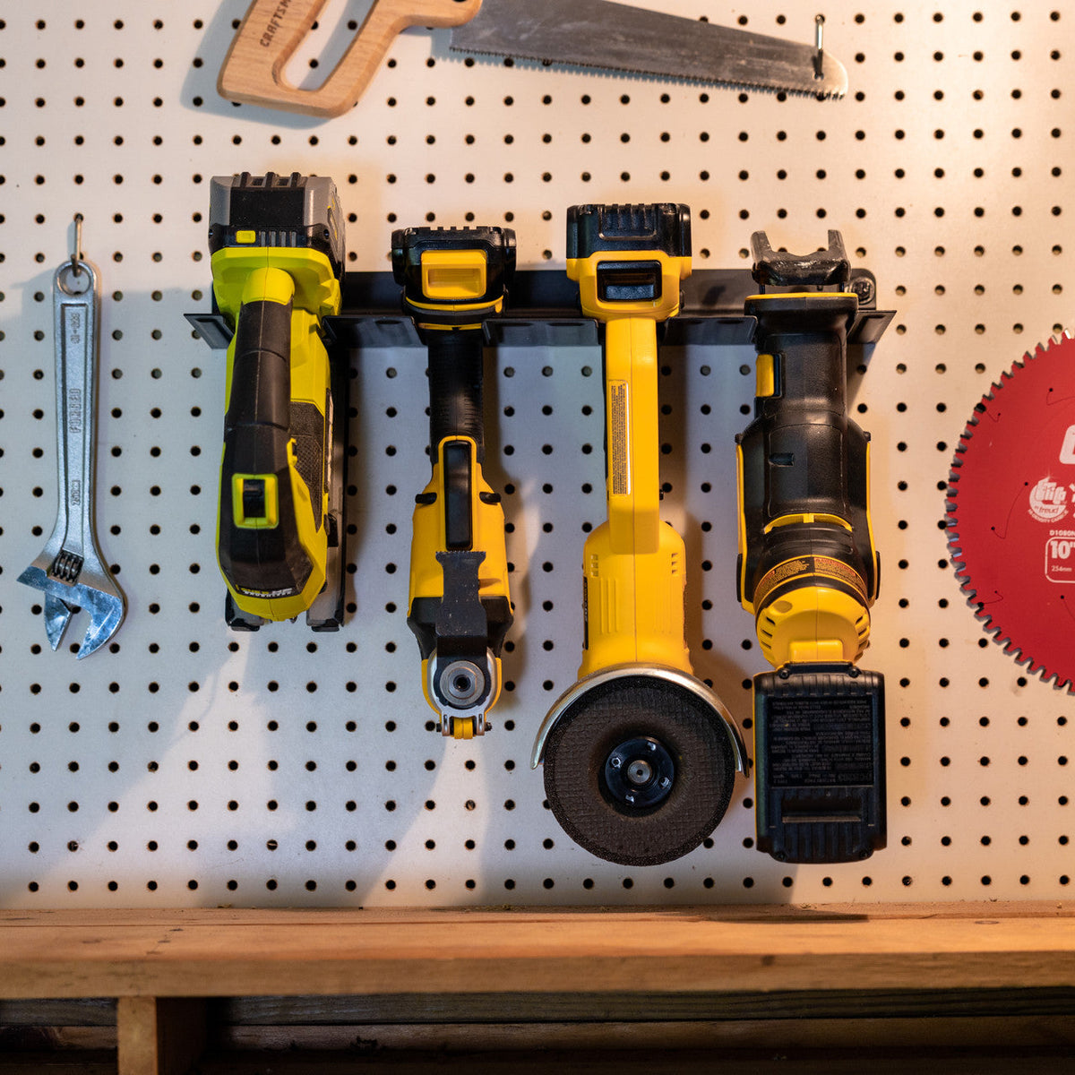 Power tool organizer on a pegboard holding drills and a grinder
