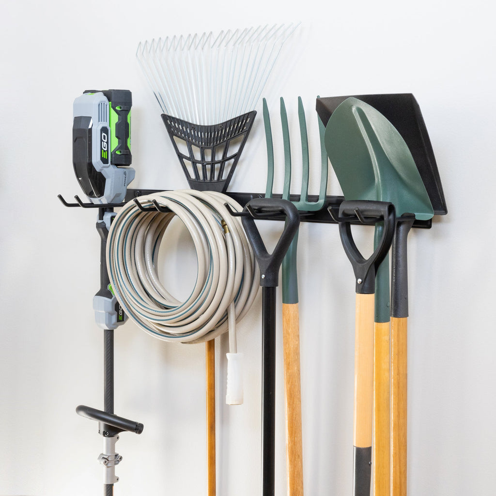 Black garden tool organizer holding a trimmer, hose, rake, pitchfork and shovels