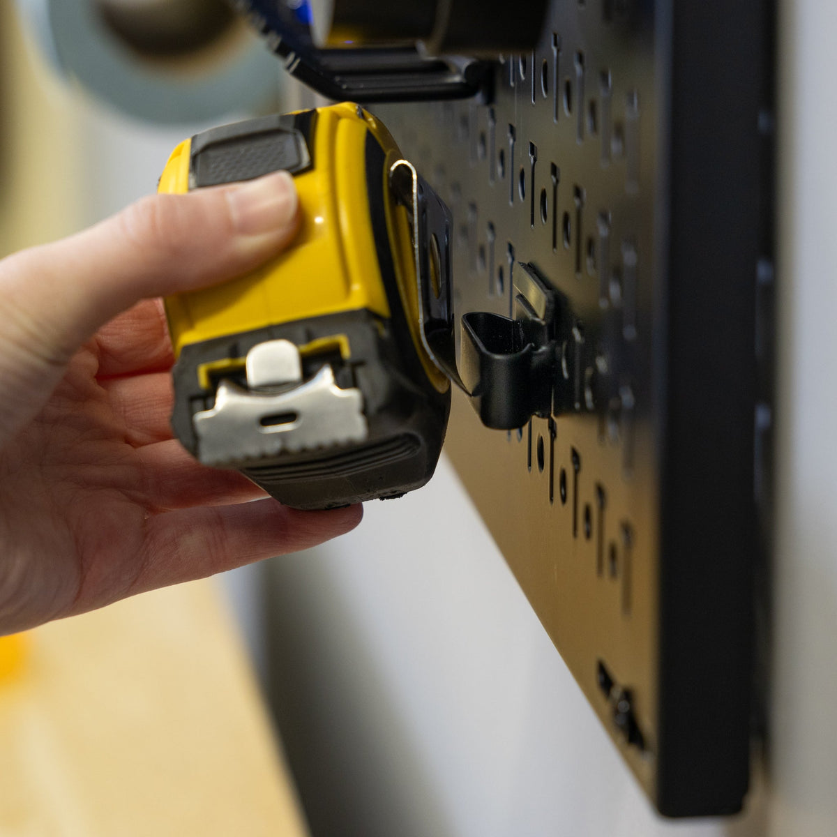 Hand hanging a tape measure on the pegboard