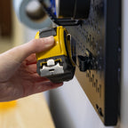 Hand hanging a tape measure on a pegboard hook
