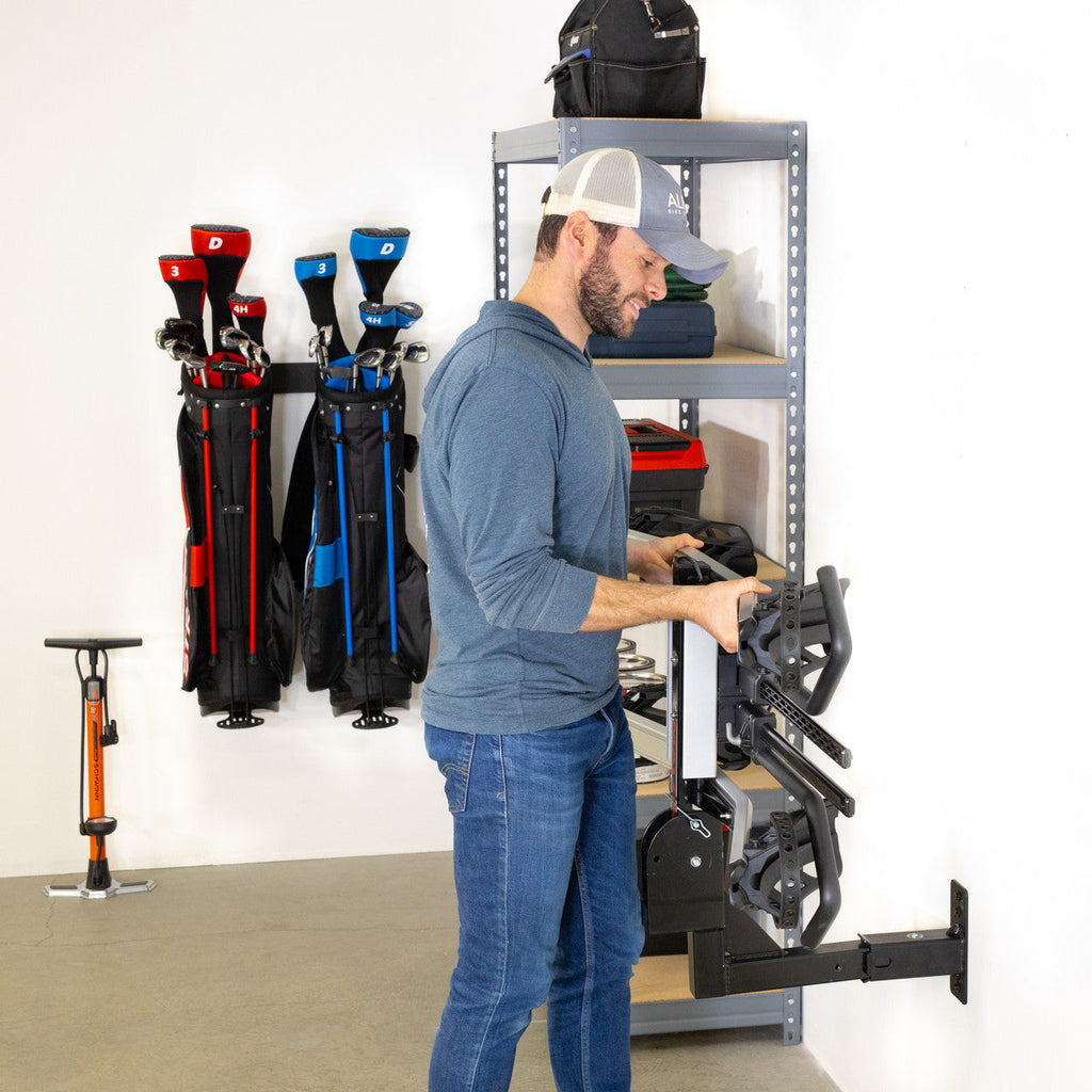 Person storing a hitch cargo rack on the 2-inch hitch wall mount next to garage shelving