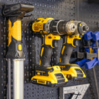 Drills and a work light stored on pegboard accessory holders