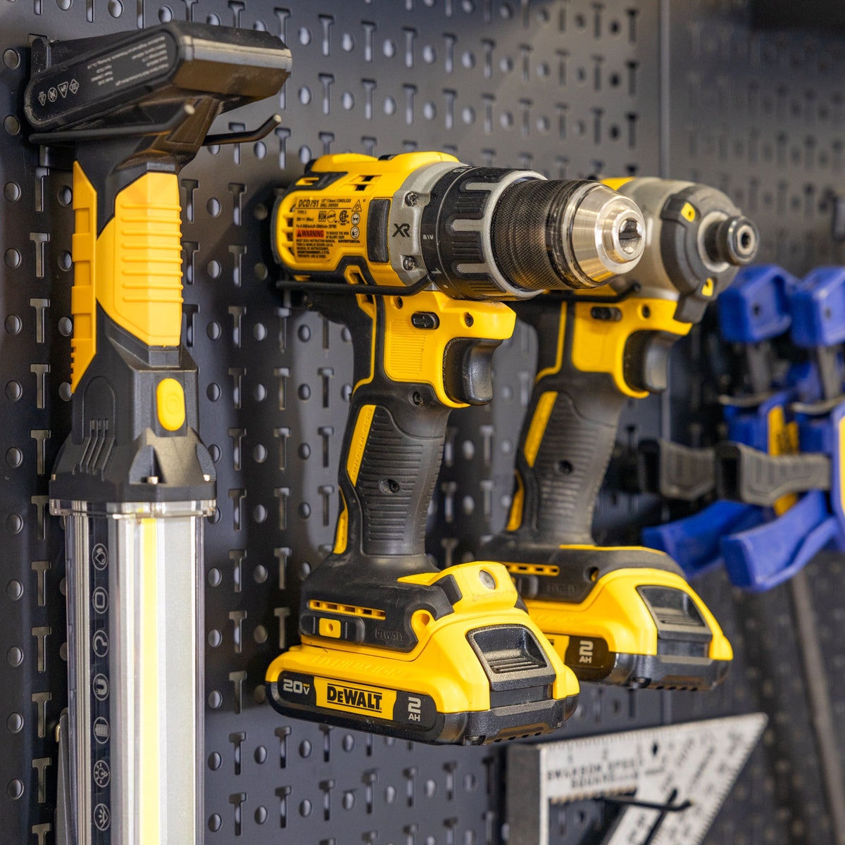 Drills and a work light stored on pegboard accessory holders
