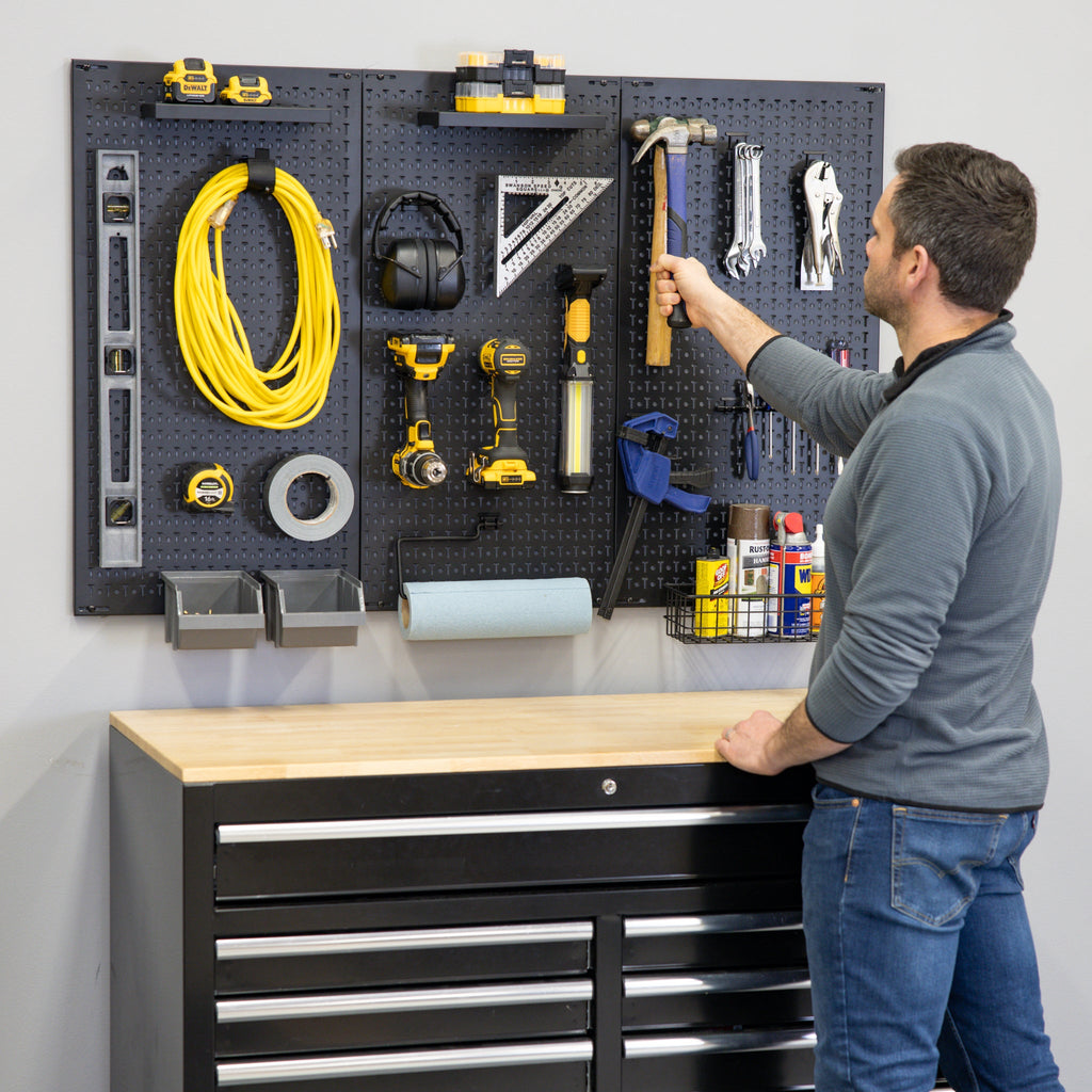 Man reaching for a tool on the pegboard above a tool chest