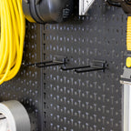Close-up of pegboard hooks holding an extension cord and tape