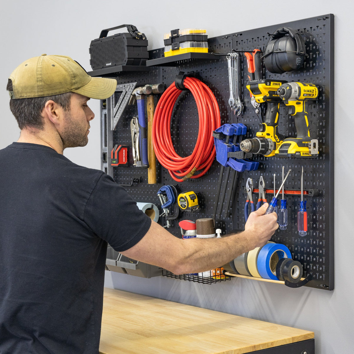 Man taking pliers from the PRO pegboard above a workbench
