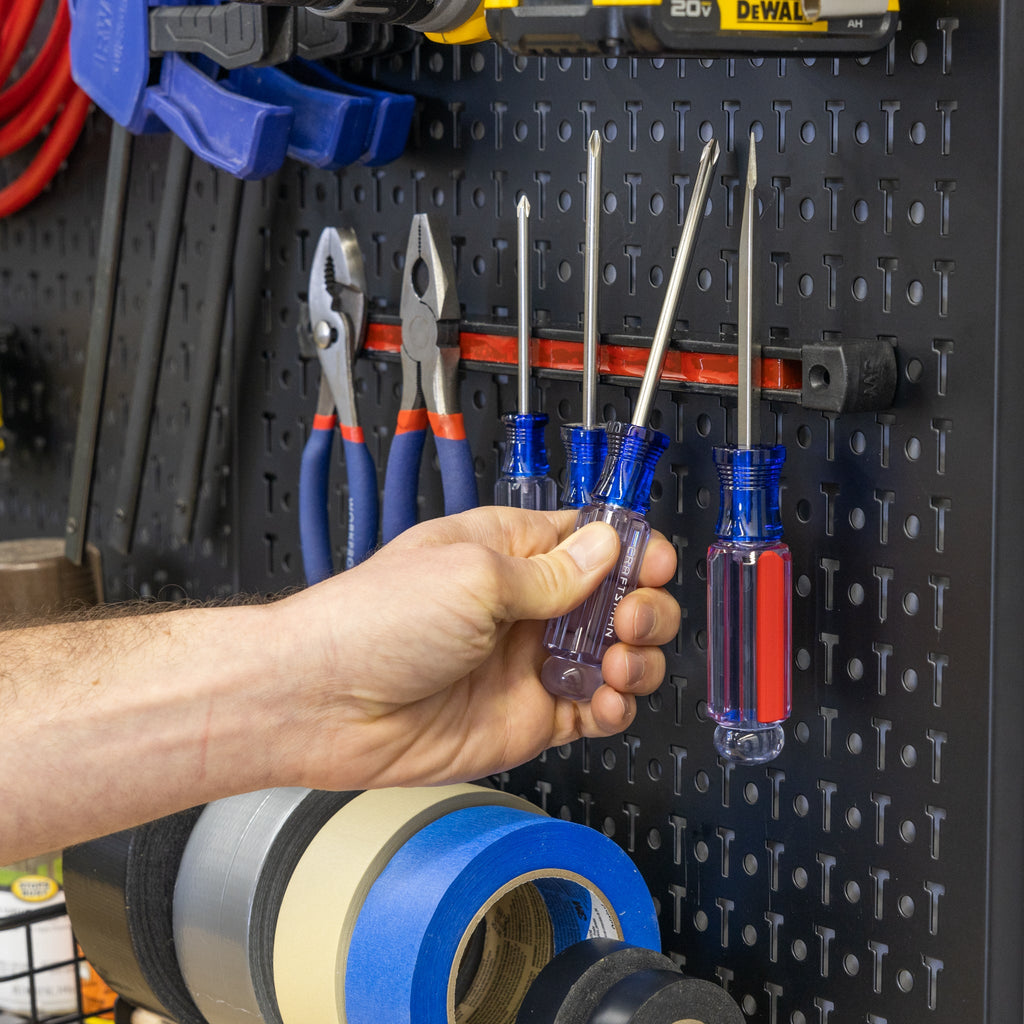 Hand taking a screwdriver from the Pegboard Pro magnetic strip