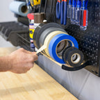 Hand taking a roll of tape from the pegboard tape holder