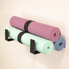Three yoga mats stored on two minimalist wall hooks