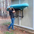 Man lifting a kayak onto the outdoor wall rack