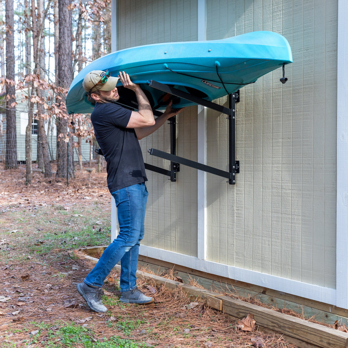 Man lifting a kayak onto the outdoor wall rack