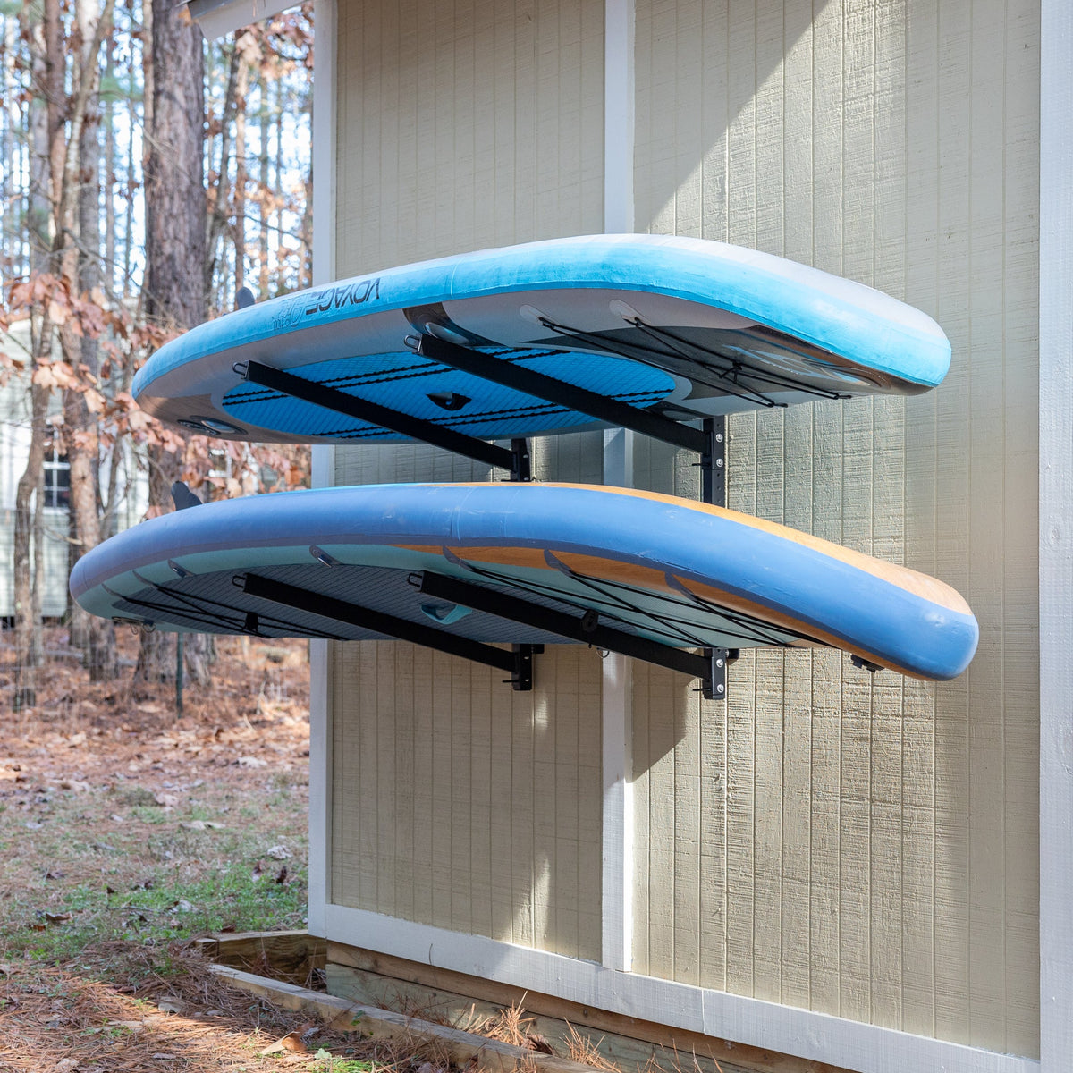 Two paddleboards stored on the outdoor wall rack
