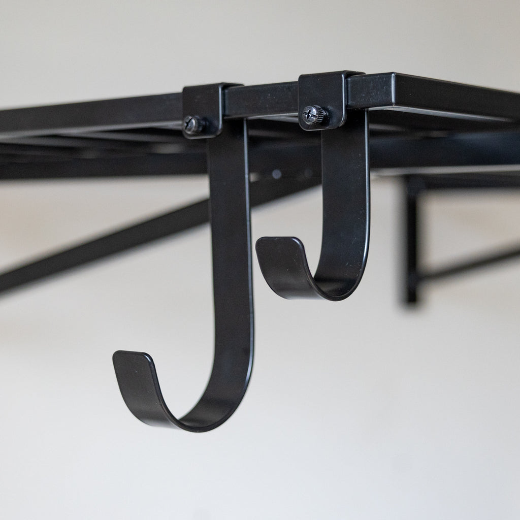Two black shelf hooks clipped under a wall shelf