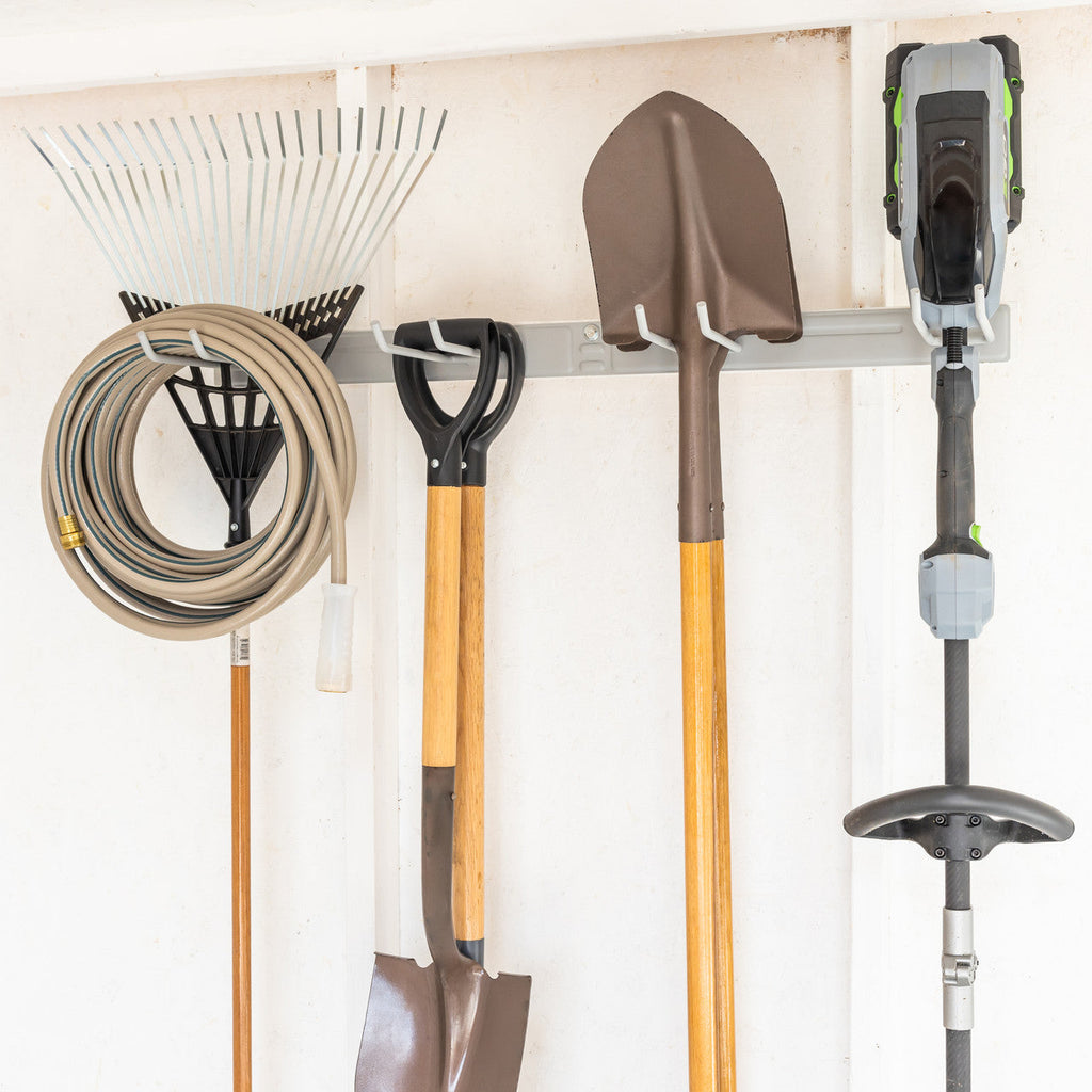 Hose, rake, shovels and a string trimmer hung on the gray organizer
