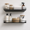 Two black Haven wall shelves with guard rails holding bathroom jars, bottles and towels