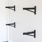 Four black DIY shelf brackets mounted on a wall without shelves