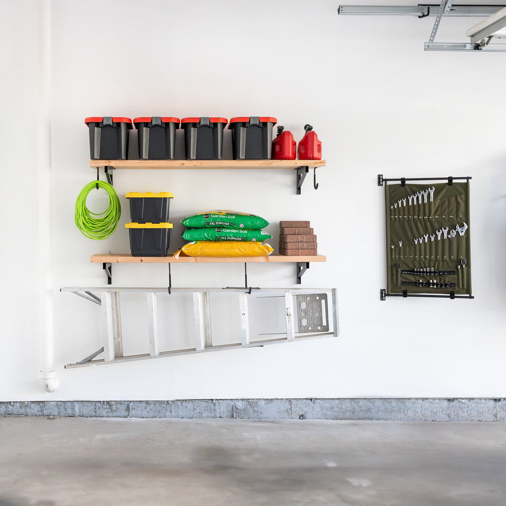 Garage wall with two DIY bracket shelves holding bins and a ladder hung below