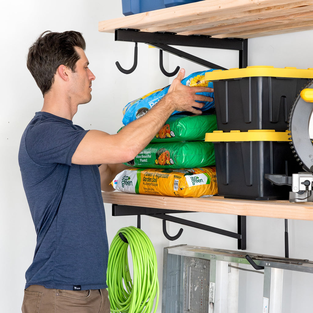 Man placing a bag of potting mix on a DIY bracket shelf