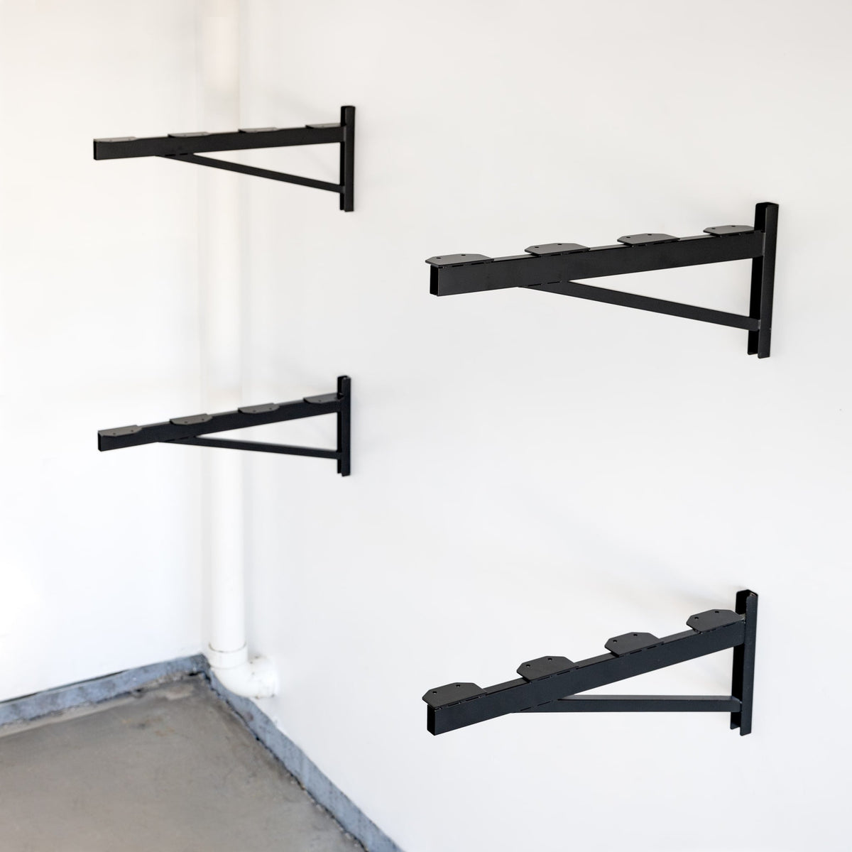 Four black 2 x 4 ft DIY shelf brackets mounted on a wall without shelves
