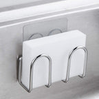 Stainless steel adhesive sponge holder mounted inside a sink and holding a white sponge
