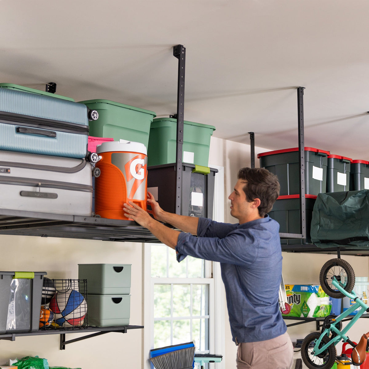 Person placing a cooler on an overhead ceiling rack loaded with bins