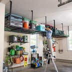 Person on a ladder loading bins onto overhead racks above garage wall storage