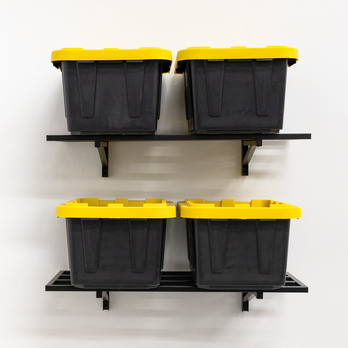 Four storage totes on two black 1 x 2 ft wall shelves, front view