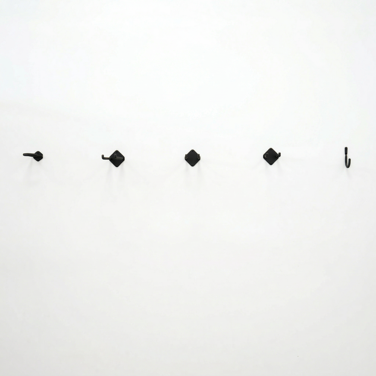 Row of Simple Hooks mounted on a white wall, front view