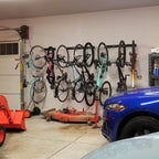 Garage wall lined with bikes on Blackstone racks beside a parked car