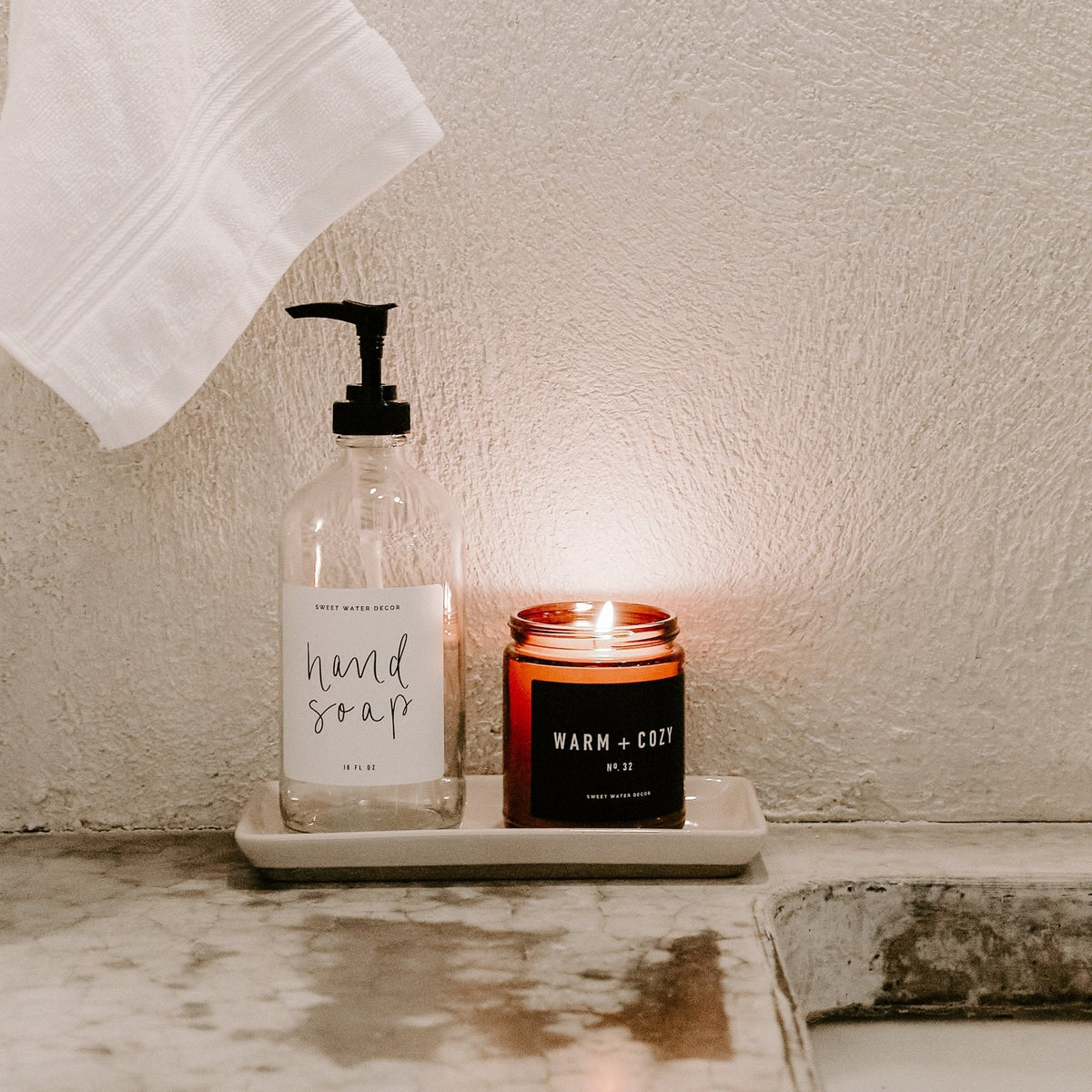 Cream stoneware tray holding a hand soap dispenser and a lit candle