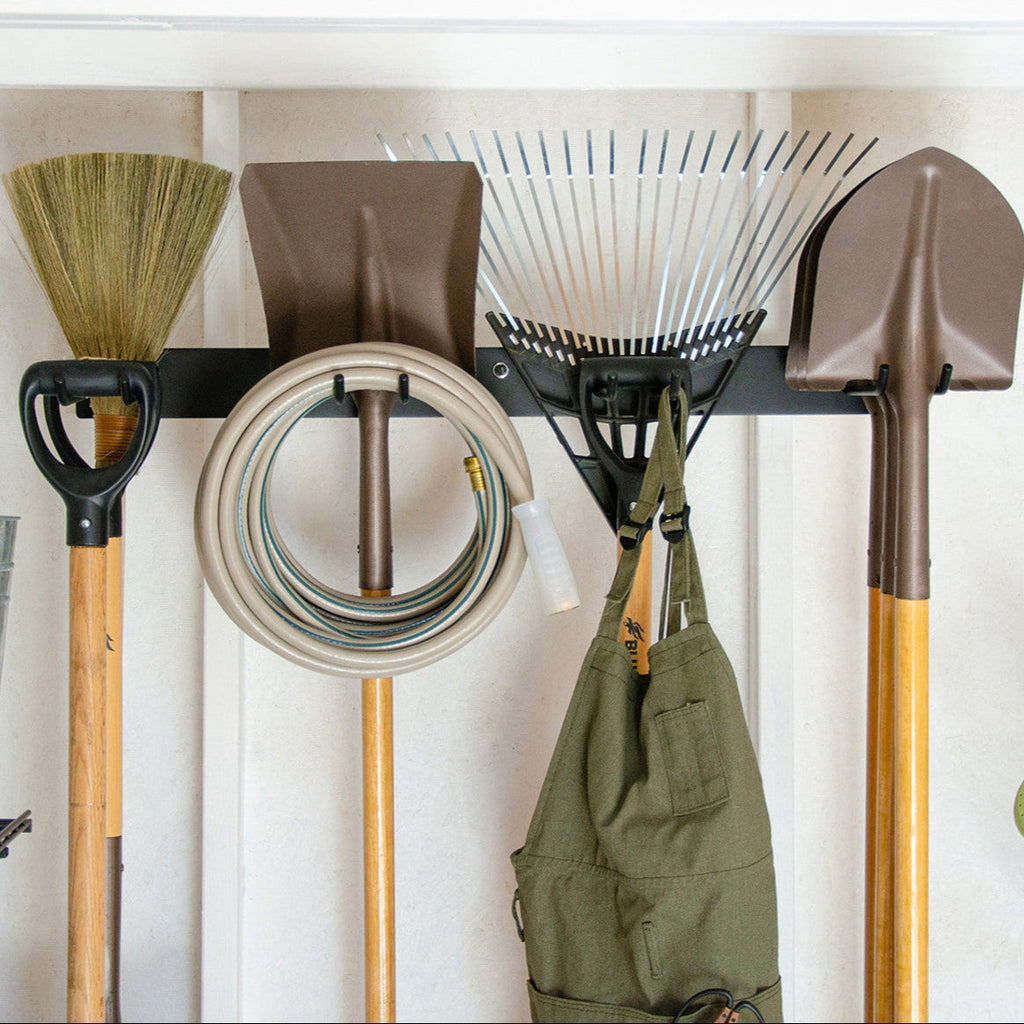 Black tool organizer holding a broom, shovels, a hose, rake and apron