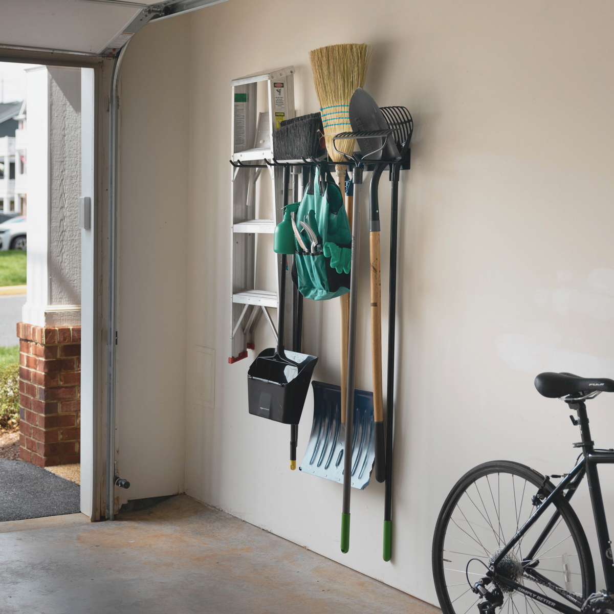 Garden tool organizer on a garage wall beside a bike