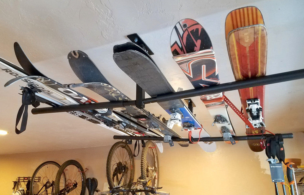 Snowboards and skis stored on the ceiling rack above bikes
