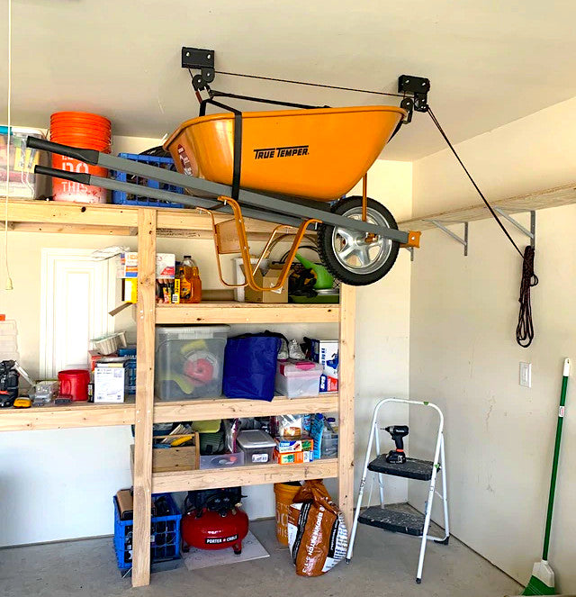 Wheelbarrow stored overhead on the hoist above garage shelving