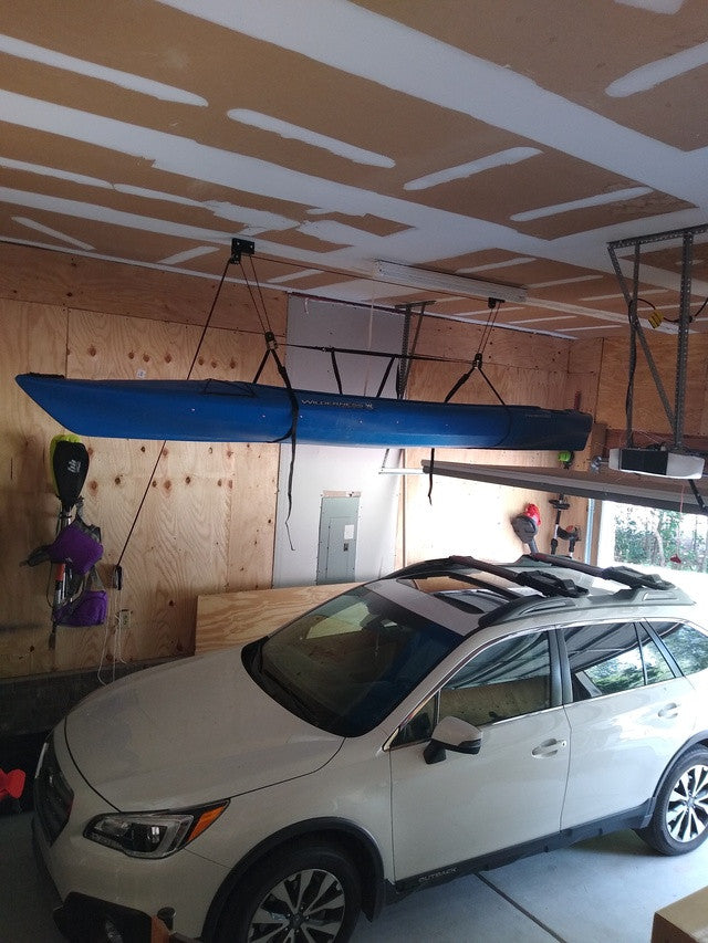 Kayak stored on the ceiling hoist above a parked car