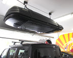 Cargo box stored on the ceiling hoist above an SUV in a garage