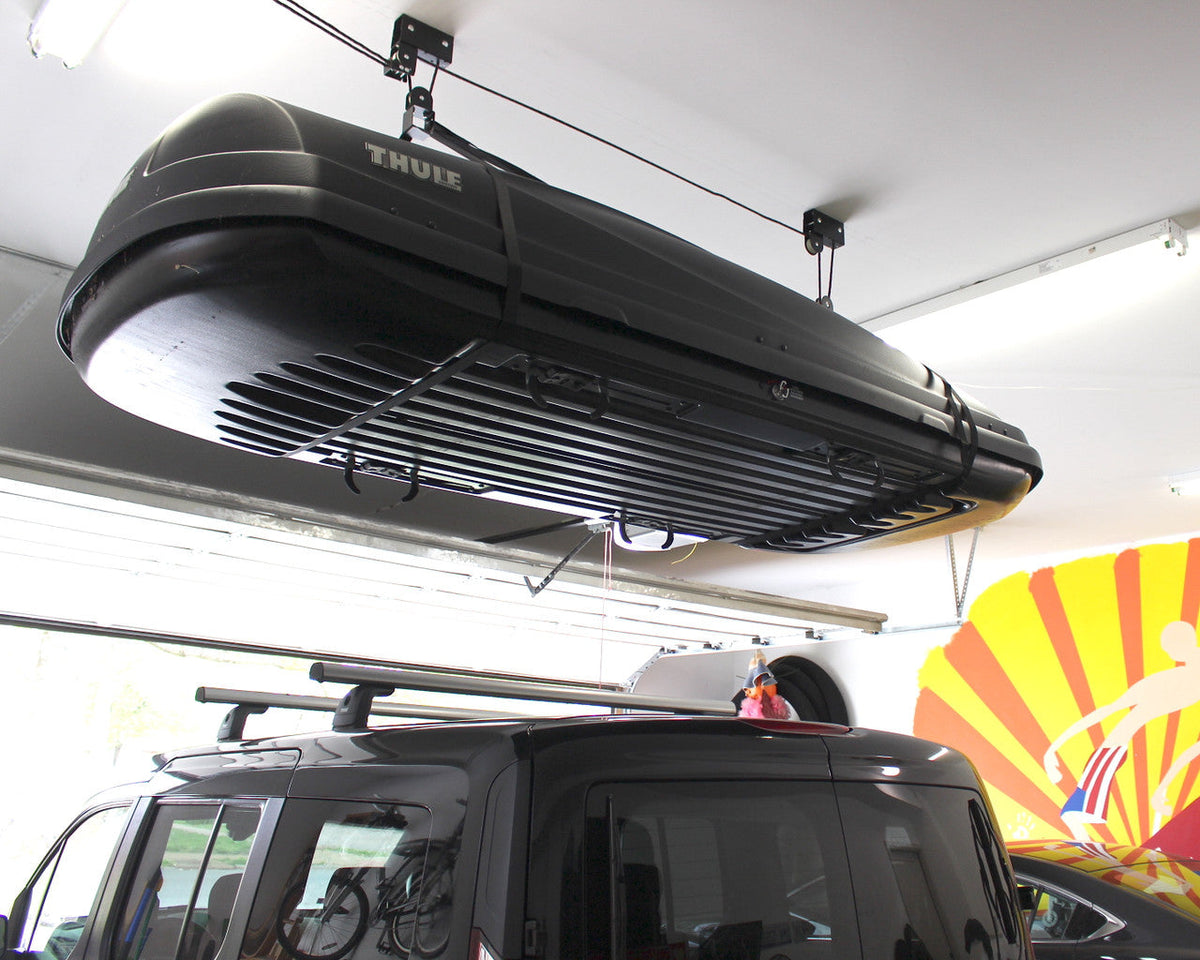 Cargo box stored on the ceiling hoist above an SUV in a garage