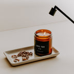 Cream stoneware tray holding a lit amber jar candle and used matches
