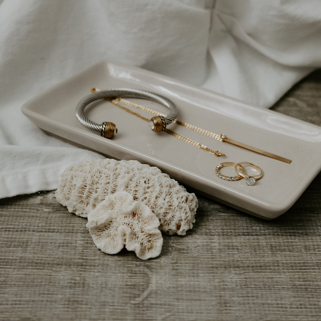 Cream stoneware tray holding bracelets and rings